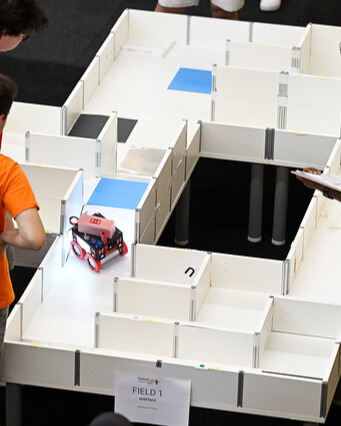 A robot part-way through a RoboCupJunior Rescue Maze arena, walled tiles marked with coloured victims.